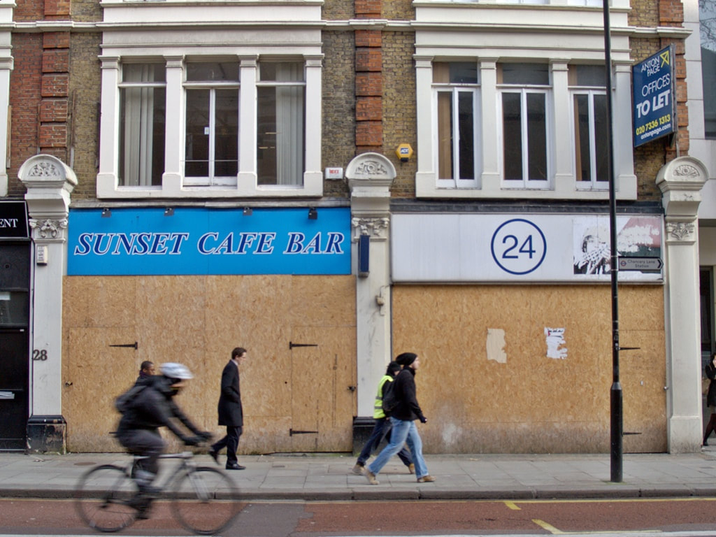 A cyclist and pedestrians pass the boarded up Sunset Cafe Bar on Gray's Inn Road, in Holborn, WC1