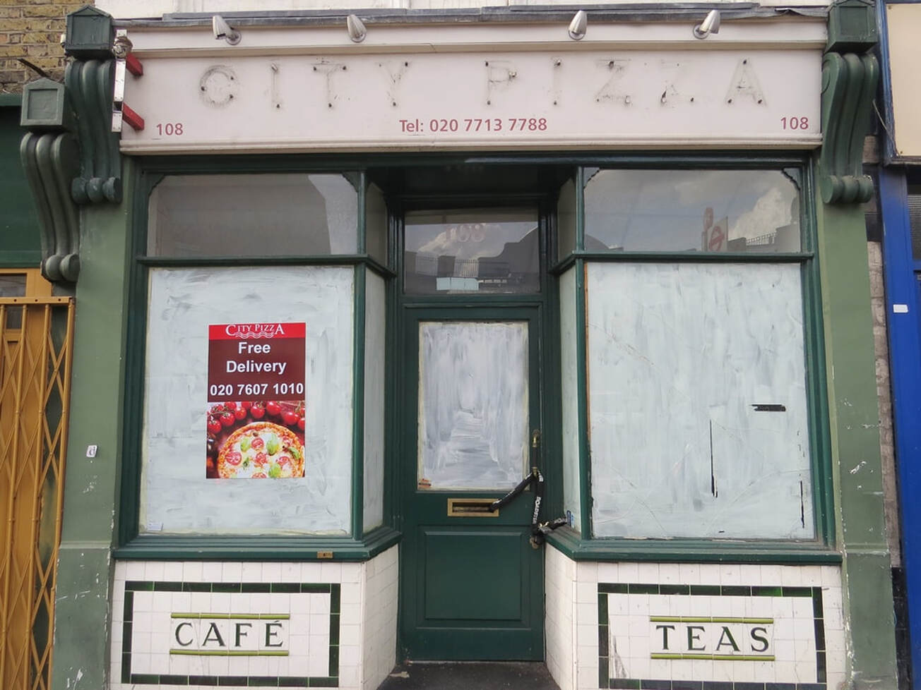 derelict cafe with ceramic white tiles with green lettering on Pentonville Road in Islington, London