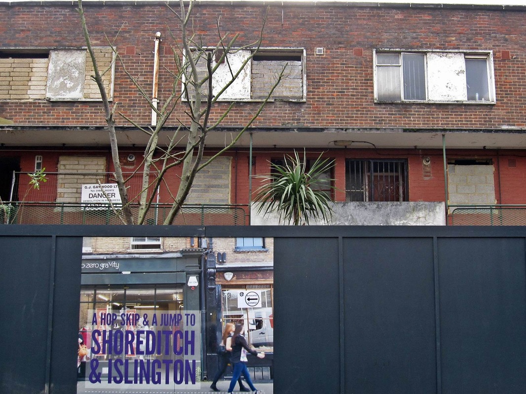 The last decaying empty flats in Laburnum Rd in Haggerston. The billboard says: A hop skip and jump to Shoreditch & Islington