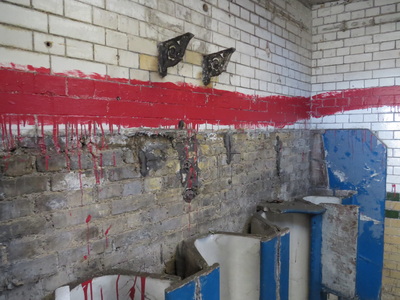 The arts installation involved red paint which is why some of the tiles are daubed in it. This red paint is symbolic of the statue which sits above the toilets. The statue is of the then Liberal Prime Minister William Gladstone 
