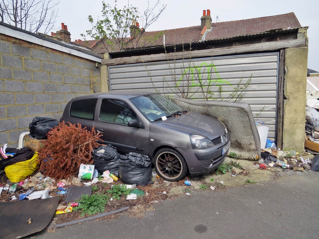 Dumped car and abandoned mattress and dead Xmas tree amonst rubbish sacks flytipped in Crodon, South London