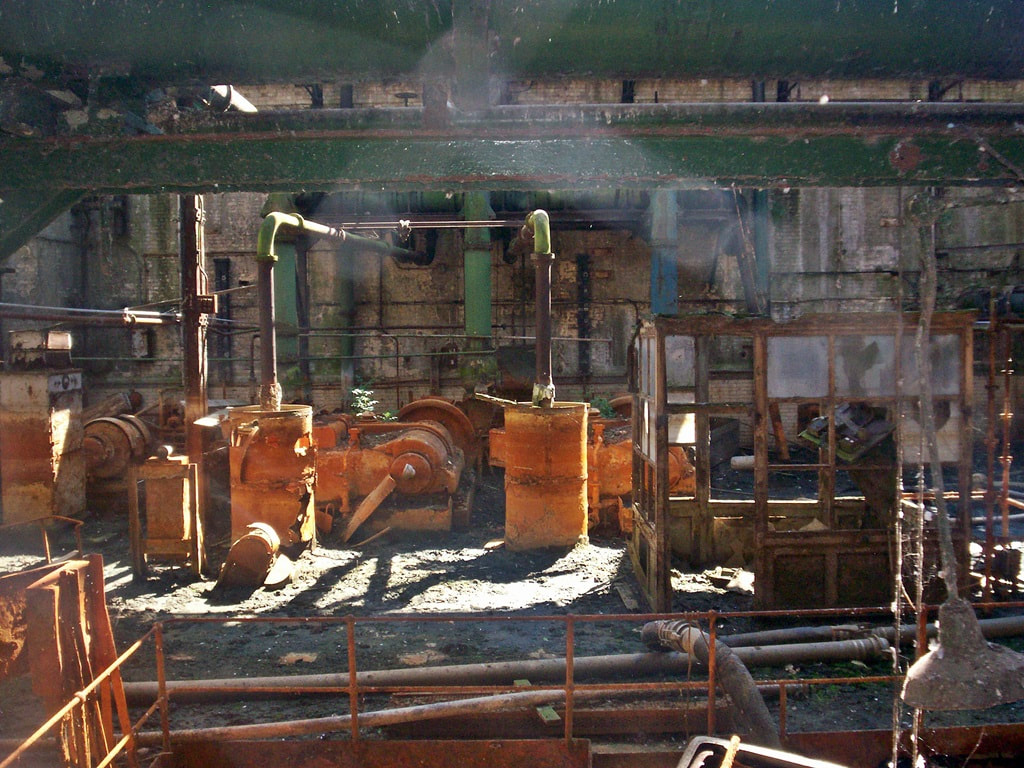 Abandoned industrial engineering area in Victorian workshop showing rusted barrels and machinery