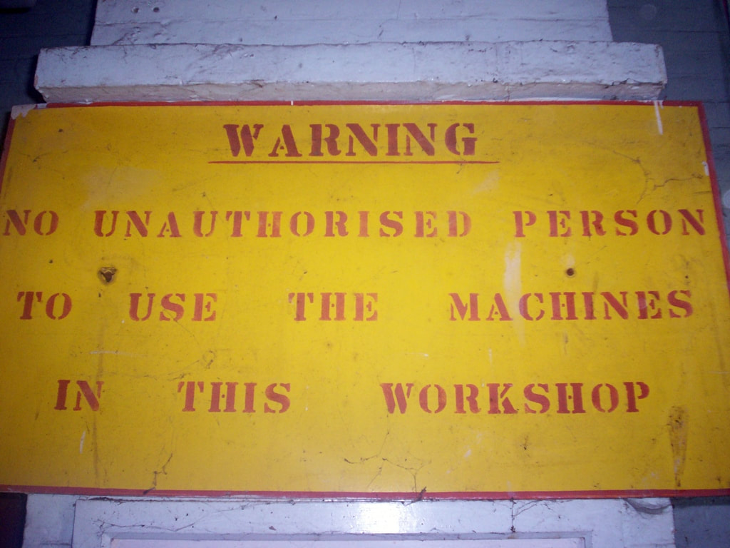 Yellow sign with red writing warning of no unauthorised persons to use the machines in this workshop