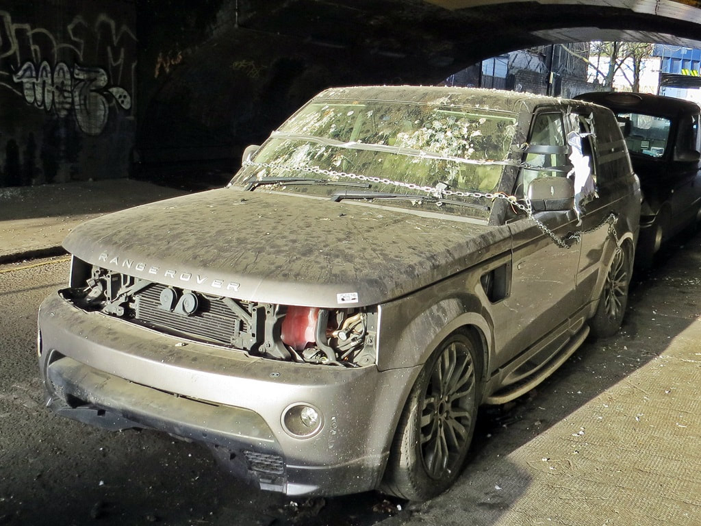 Abandoned Range Rover under railway arches in Bethnal Green, East London