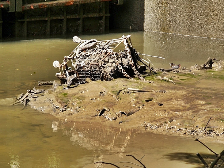 Abandoned supermarket shopping trolley disposed of in the Beverley Brook in Barnes, South West London