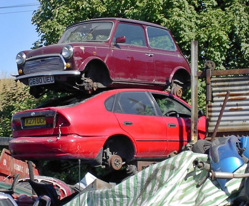 Austin Mini on top of pile of cars at salvage yard in East London
