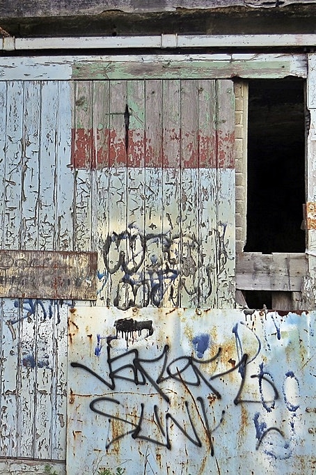 Peeling paint and rotting wood on doors of derelict building in Silvertown, East London