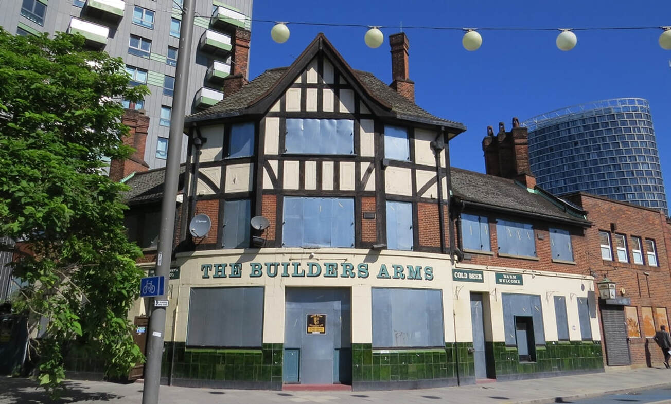 The Boarded up Builders Arms mock Tudor pub on Stratford High Street beneath blue sky