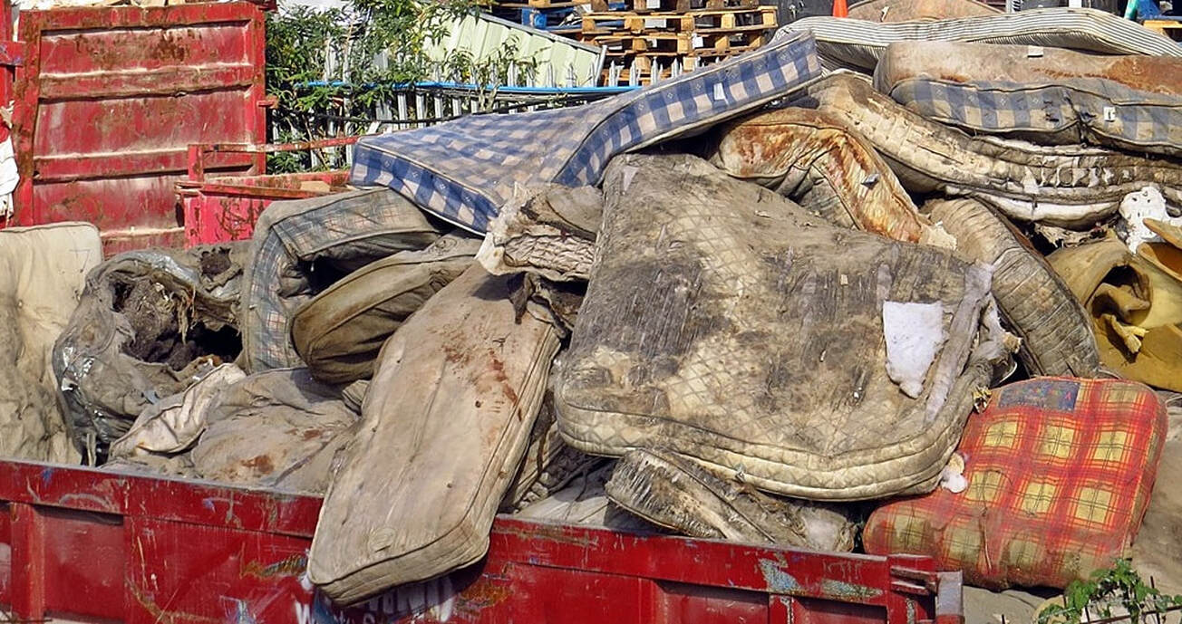Pile of dirty abandoned mattresses on a skip in South London