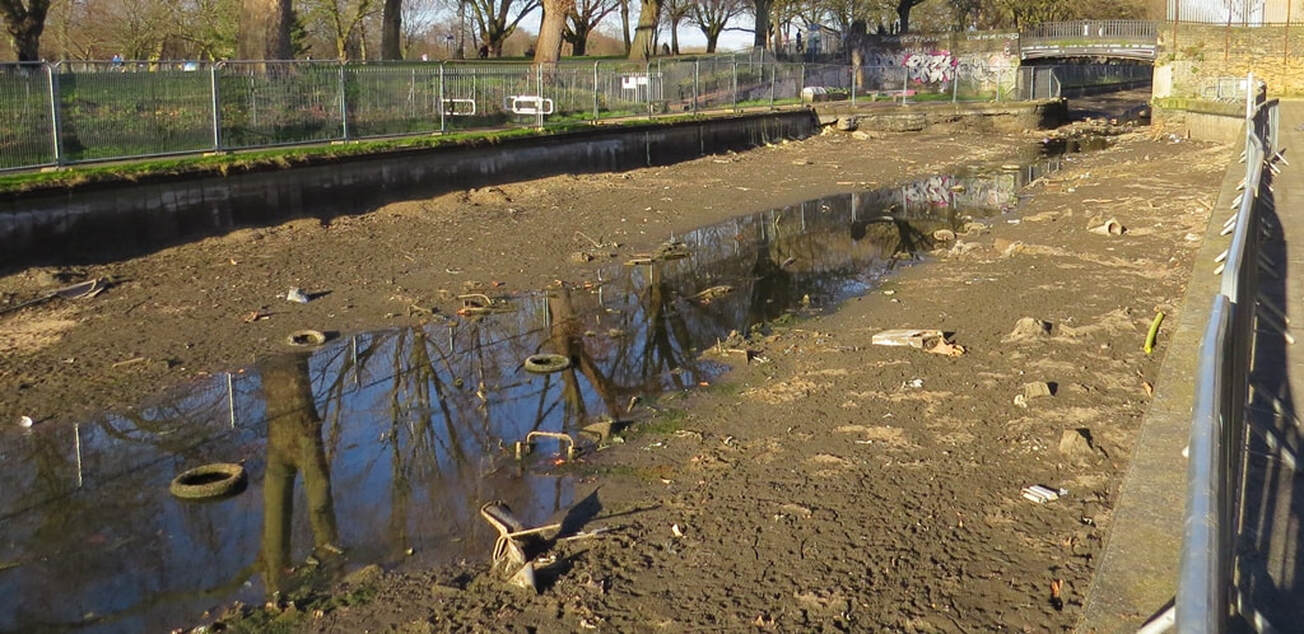 Picture of drained East London canal showing mud and debris including discarded tyres  