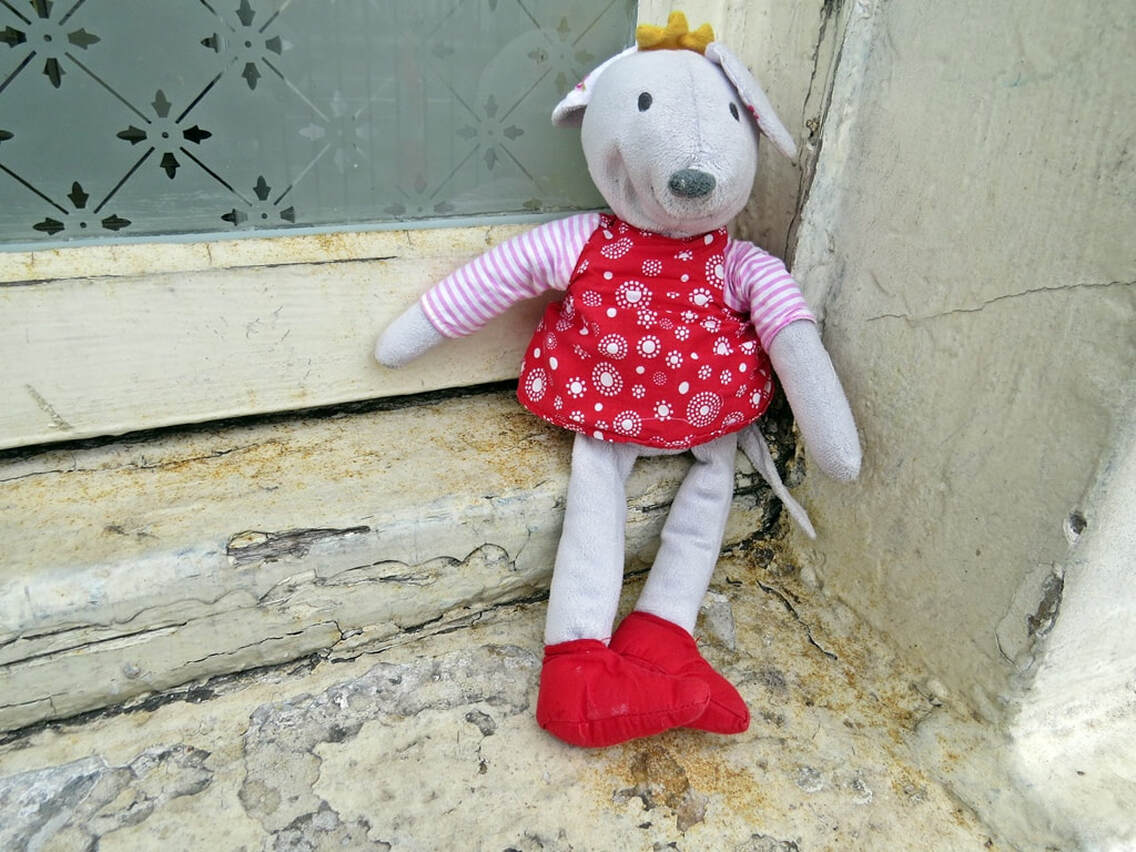 Abandoned child's cuddle mouse toy sitting on window ledge of decaying building in South London