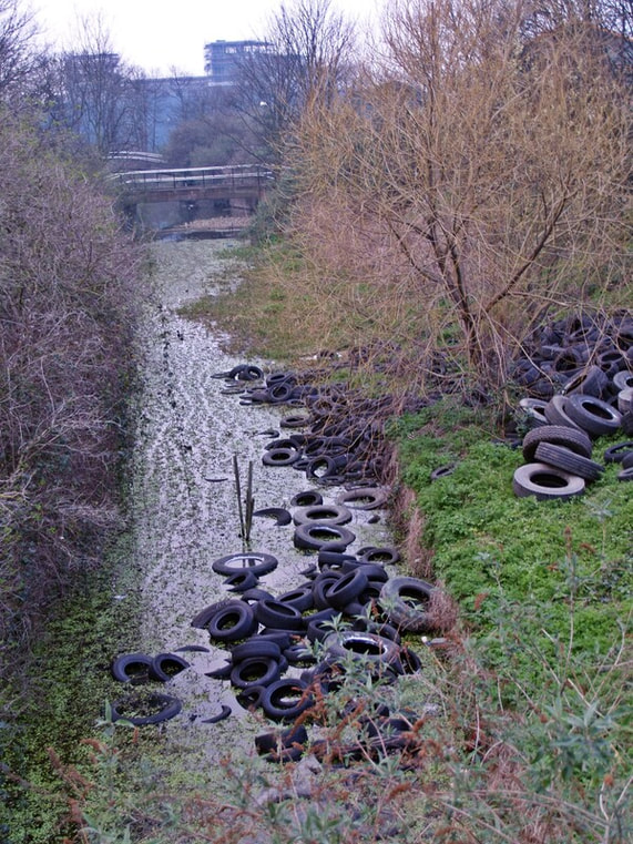 Picture of the neglected  Pudding Mill River full of flytipping inc tyres before the Olympics Stadium was built over it