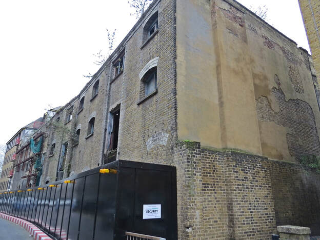 ​Red Lion Court in Wapping was a partially demolished warehouse located on Reardon Path (previously called Red Lion Street).During the 1940s this Victorian building  was under the ownership of Pye Storage Ltd, then Coordinated Traffic Services and by The Mentex Co from the 1960s where the building is listed as a cotton and plastics factory using recycled cotton combined with plastic to make hosepipes .