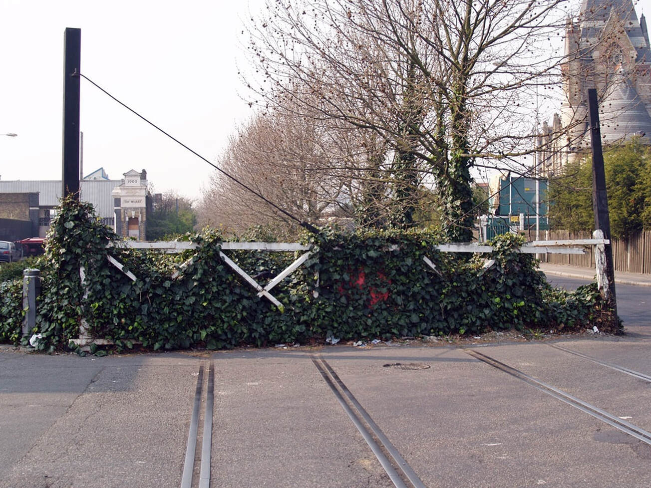 Derelict overgrown wooden level crossing gates at the disused Silvertown Tramway