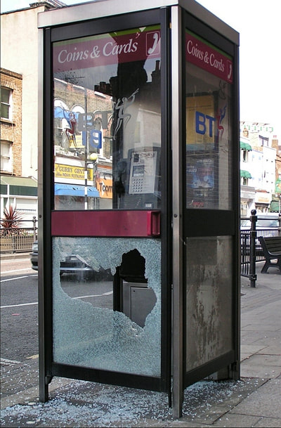 smashed glass panel of phone box in Mile End