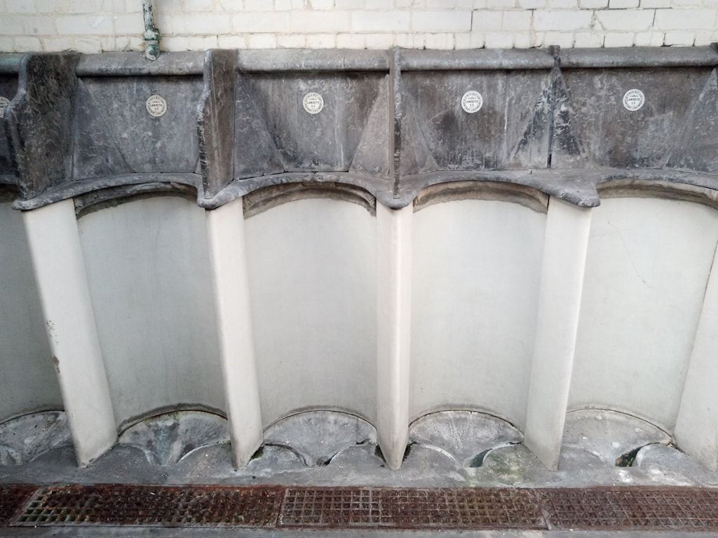  Disused public toilets in Kennington with white marble urinals with black marble modesty screens and ceramic roundels inscribed "B Finch and Co Limited, Sanitary Engineers, Lambeth SE"