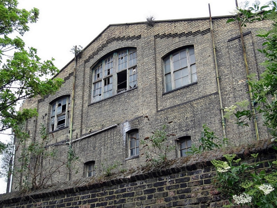 Broken windows of derelict Kings Cross warehouse known for prostitution and drug abuse