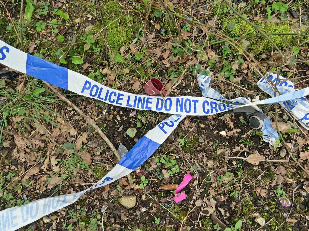 Police do not enter blue and white crime scene tape on the grass in North London