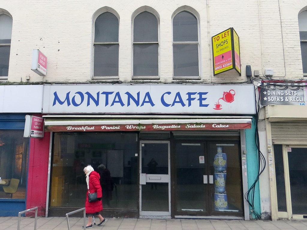 An Elderly lady in a red coat walks past the closed down Montana Cafe in Sutton.