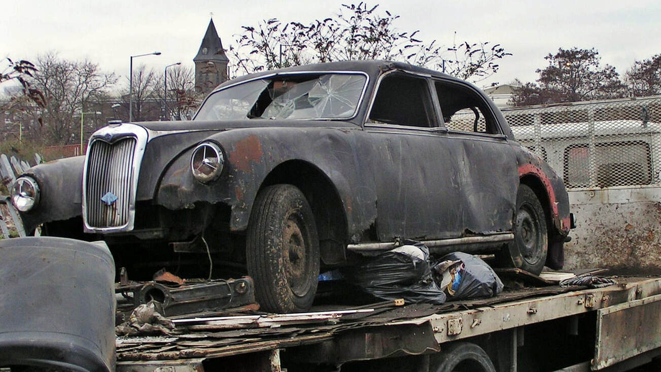 smashed up vintage car on back of trailer in East London