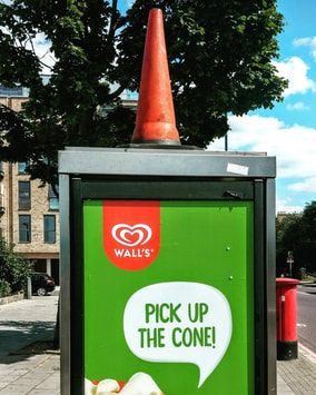 Walls Pick up the cone ad on phonebox with traffic cone on it in Peckham
