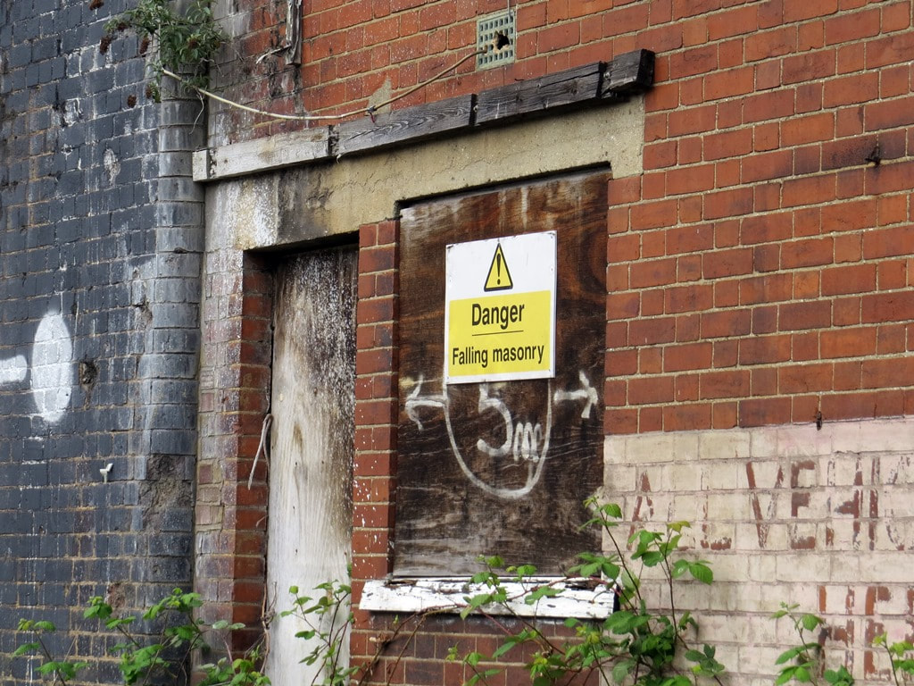 Danger falling masonry sign at derelict railway arches in East London