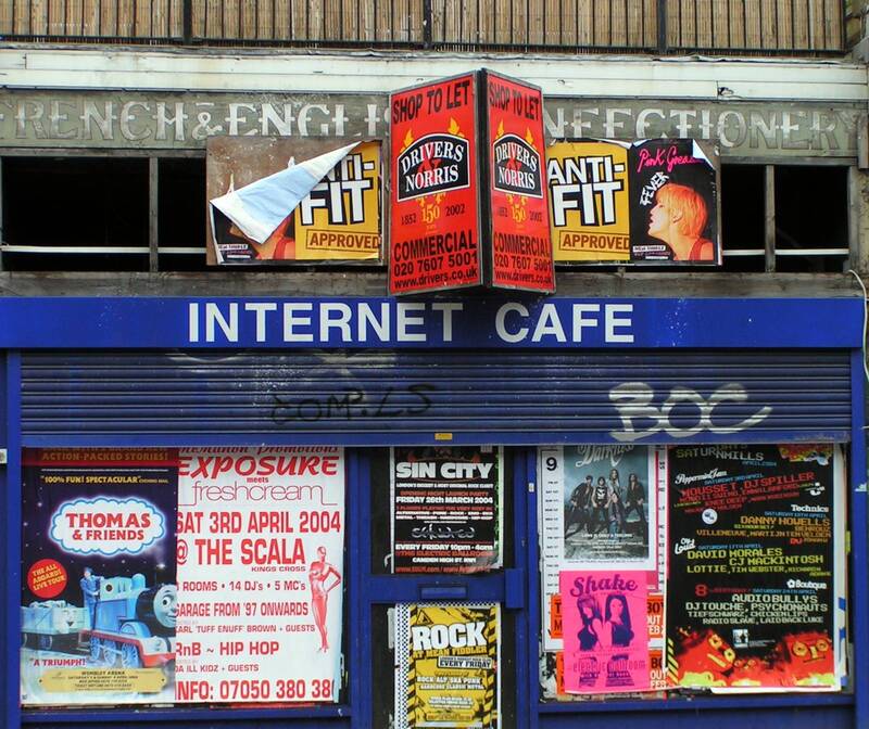 Derelict Internet Cafe, covered in fly posters in Tufnell Park with ghost sign for a French and English confectioners visible above